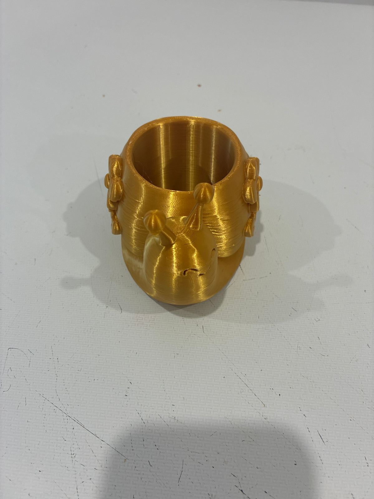 Gold 3D printed crown-shaped cup holder on white surface